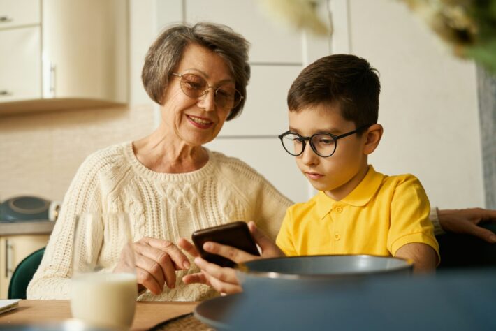 Kid helping to grandmother find information in smartphone