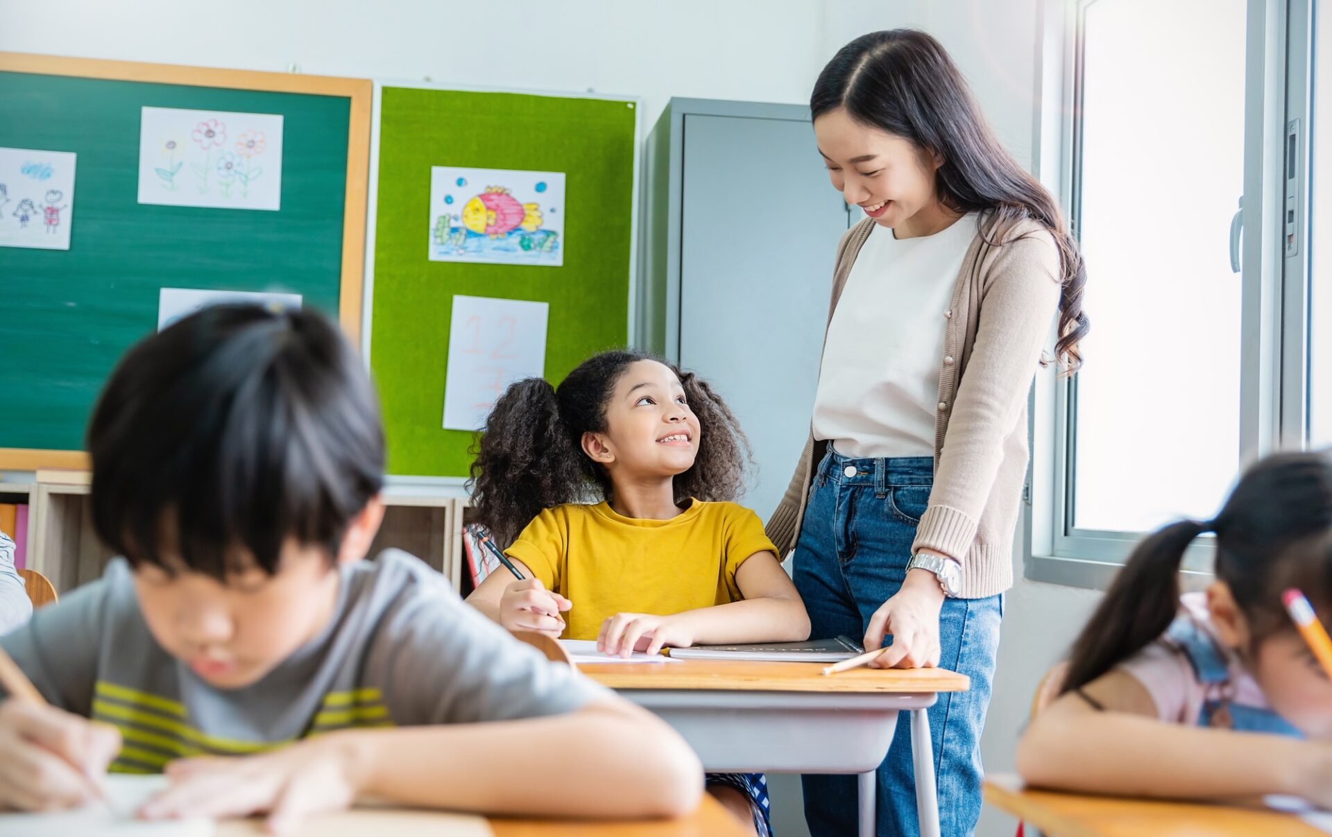Pupil black girl with teacher in classroom at elementary school.
